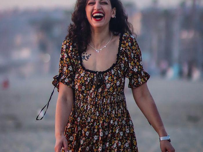 Smiling woman stretching outdoors during a beautiful sunset, feeling vibrant and energetic.