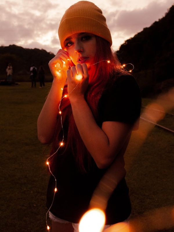 Woman in a calm, balanced pose against a dark background with sunset-colored light.